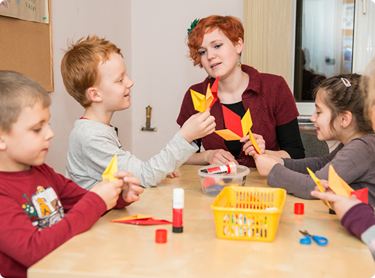 lektorka robi kwiat z papieru wraz z dziećmi