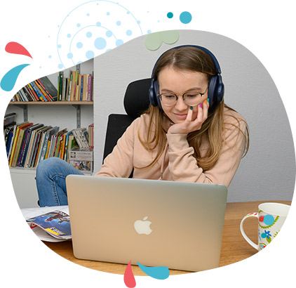 dziewczyna w słuchawkach na uszach siedzi przed otwartym komputerem