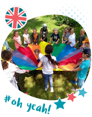 dzieciaki wesoło bawią się na dworze kolorową chustą w czsie zajęć z angielskiego